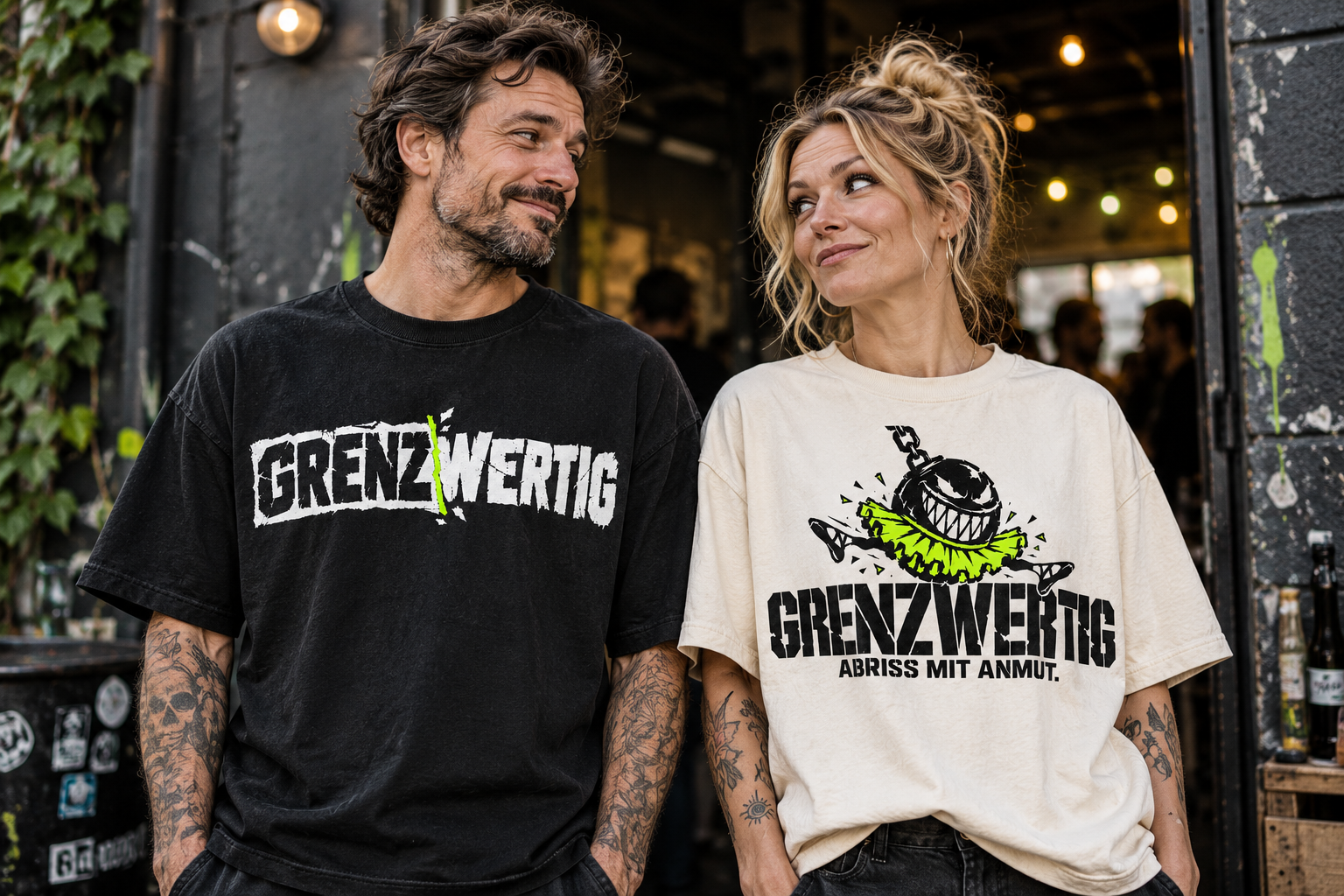 Inszeniertes Tragebild: Mann im schwarzen Logo-Shirt und Frau im Abriss-mit-Anmut-Shirt tauschen einen wissenden Blick aus
